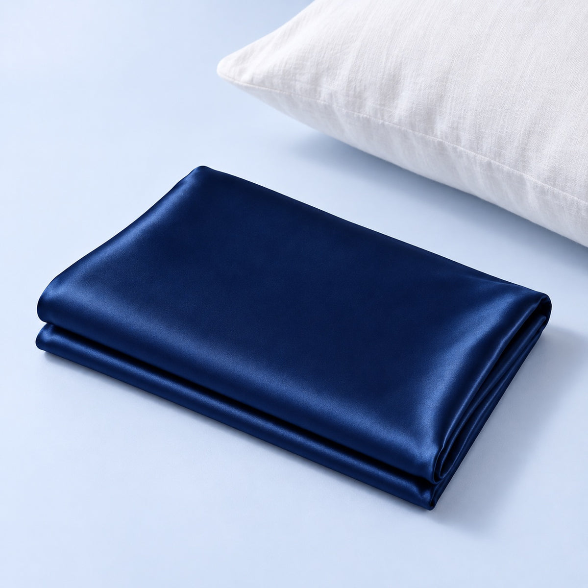 Taie en soie bleu nuit pliée sur fond bleu pâle